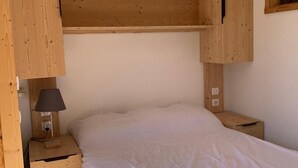 A bedroom with a wooden bunk bed, a bedside table with a lamp, and a small wooden nightstand.