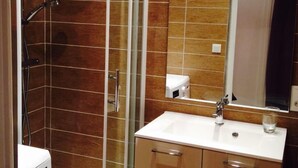 A bathroom with a glass-enclosed shower, a sink with a mirror, and a toilet.