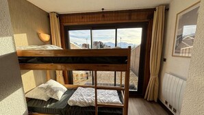 Habitación con literas y vista a las montañas a través de un ventanal amplio.