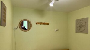 A small, single-room with two beds, a round mirror, a wooden shelf, and a ceiling light. - 30m from ski slopes, 1st floor, balcony, tv, ski locker, 32m², Alpe d'Huez (L'Alpe d'Huez)