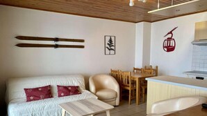 A compact living space with a sofa, a small table, a dining area, and a kitchenette. - 30m from ski slopes, 1st floor, balcony, tv, ski locker, 32m², Alpe d'Huez (L'Alpe d'Huez)