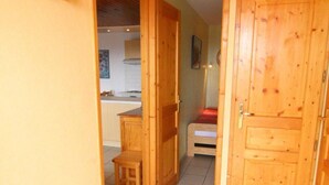 A hallway with wooden doors, a small wooden chair, and a tiled floor. - 30m from ski slopes, 1st floor, balcony, tv, ski locker, 32m², Alpe d'Huez (L'Alpe d'Huez)