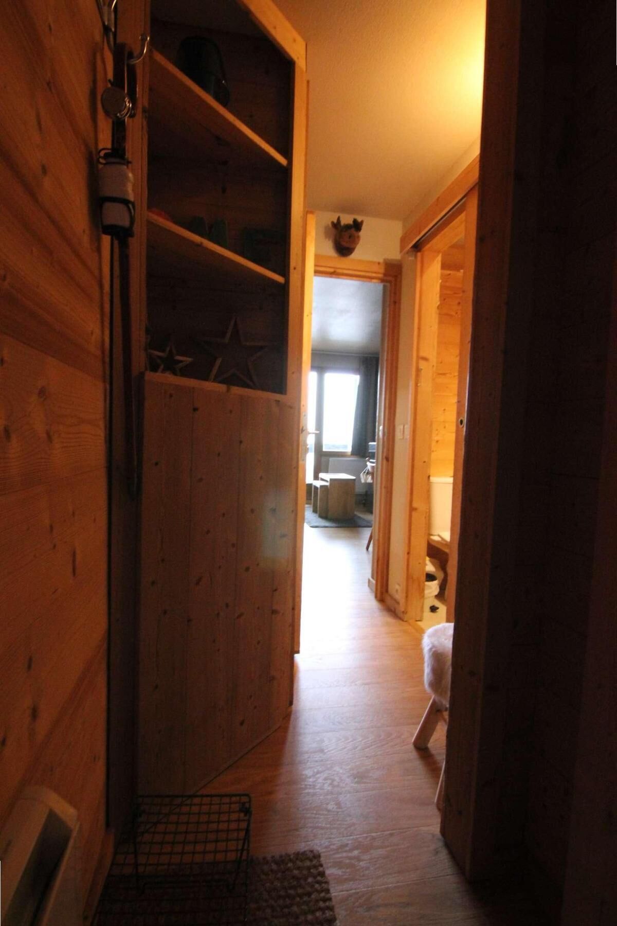 A wooden interior hallway with a door leading to a room.