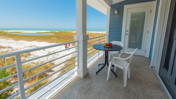 Un balcon donnant sur la plage, une table avec des chaises et une porte.