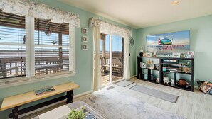 A room with a bench, a bookshelf with decorative items, a painting, and a view through a window.