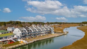 A row of waterfront cabins with balconies, a dock, and a river.