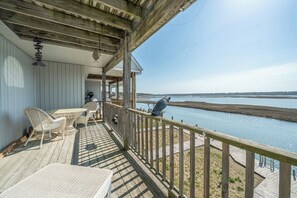 Eine Holzterrasse mit Gartenmöbeln, einem Geländer und Blick auf ein Gewässer.