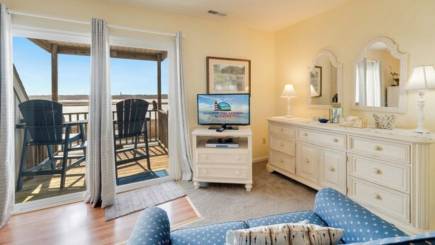 A room with a balcony, a television, a dresser, and a sofa.