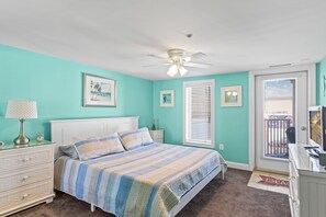 A bedroom with a bed, a ceiling fan, a dresser, a nightstand, and a window with blinds. - Belmont Towers 307 by Seaside Vacations & Sales (Ocean City)