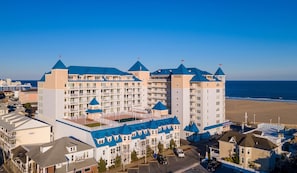 Ett stort hotell med flera torn, utsikt över stranden och en parkeringsplats.