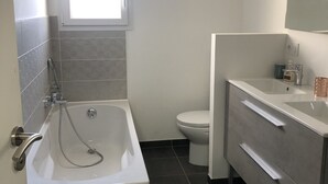 A modern bathroom with a bathtub, toilet, and vanity. - 800 M from the basin / direct access to cycle path 6 people (Andernos-les-Bains)