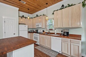 A kitchen with wooden cabinets, a refrigerator, a stove, a microwave, and a coffee maker.