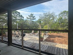 An outdoor patio with wooden flooring, metal chairs, and a barbecue grill.