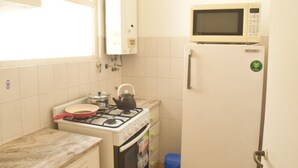 A compact kitchen with a gas stove, a microwave, and a refrigerator. - Department Moreno Center 2366 (Mar del Plata)