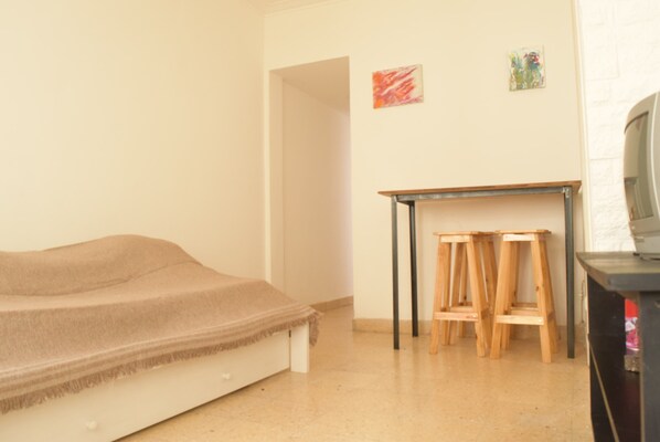 A bedroom with a bed, a small table, and two wooden stools.