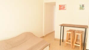 A bedroom with a bed, a small wooden table, two stools, and two wall-mounted artworks. - Department Moreno Center 2366 (Mar del Plata)