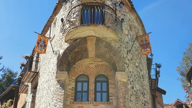 A stone building with a rounded archway, two arched windows, and a wooden door. - Loft Milan Valkyrie (Valqurico)