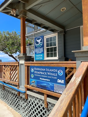 A wooden structure with a sign for the Hawaiian Islands Humpback Whale National Marine Sanctuary Visitor Center.