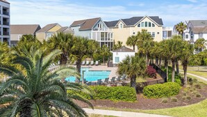 A residential area with a swimming pool surrounded by palm trees and a fence. - Summer House 204 - Pool/Beach - Ocean View! (Isle of Palms)