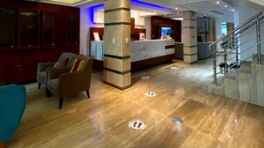 A modern lobby with a reception desk, seating area, and a staircase. - Qoya Palace - Machupicchu (Machu Picchu)