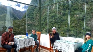 A group of people seated at a table with a mountain view through large windows. - Qoya Palace - Machupicchu (Machu Picchu)