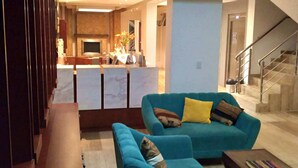 A modern living room with a blue sofa set, a coffee table, and a kitchen area in the background. - Qoya Palace - Machupicchu (Machu Picchu)