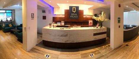 A reception area with a marble counter, a sign reading "Qoya Palace," and a reception desk.
