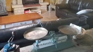 Ein Wohnzimmer mit Kamin, einer schwarzen Ledersofa, einem Holztisch und einer alten Waage.