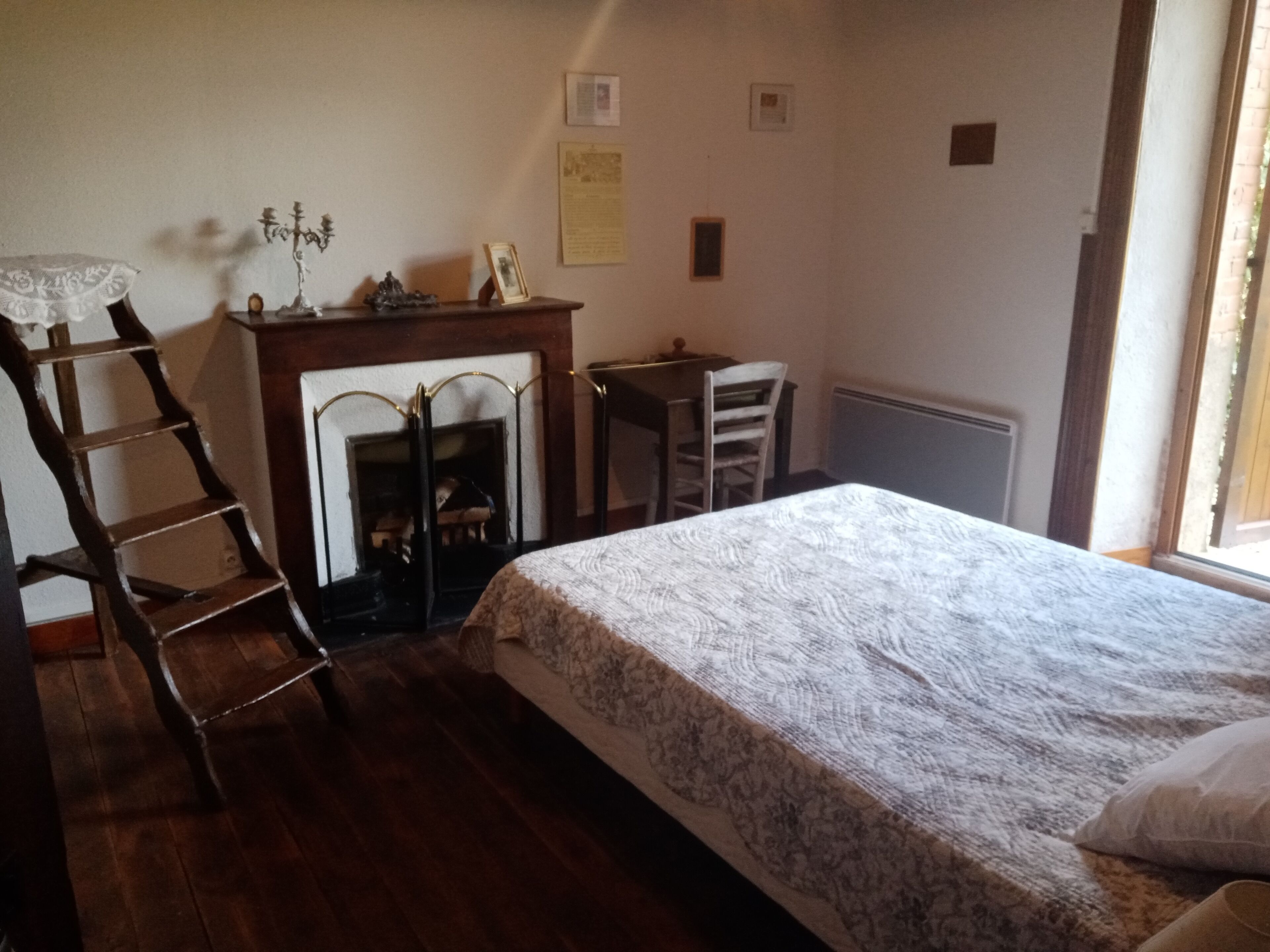 Un dormitorio con cama, una escalera de madera, chimenea, escritorio y silla.