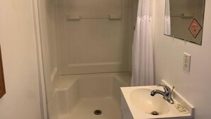 Ein Badezimmer mit Dusche, Waschbecken und Spiegel.