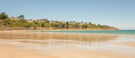 A beach with a clear view of houses on a hillside.