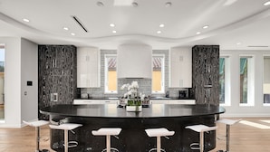 Une cuisine moderne dotée d’un îlot central, de tabourets de bar et d’un revêtement mural décoratif au motif original.