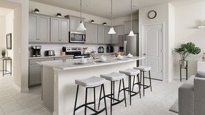 Una cocina moderna con gabinetes grises, una isla central con taburetes de bar, electrodomésticos de acero inoxidable e iluminación colgante.