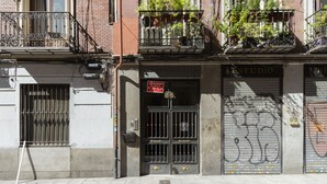 Un edificio con una puerta metálica cerrada, un balcón con plantas y un letrero que dice 'ESTUDIO'.