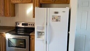 A kitchen with wooden cabinets, a stainless steel stove, and a white refrigerator.