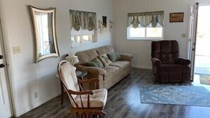 A living room with a sofa, a rocking chair, a brown recliner, a small table, and a patterned rug.