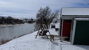 A snowy landscape with a wooden swing set, a red building, and a green garage door.