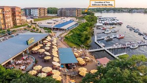 Un espace situé au bord de l’eau, doté d’une terrasse extérieure, d’un patio couvert et d’un quai où sont amarrés des bateaux.