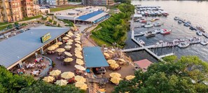 A waterfront area with outdoor seating, a covered patio, and a dock with boats.