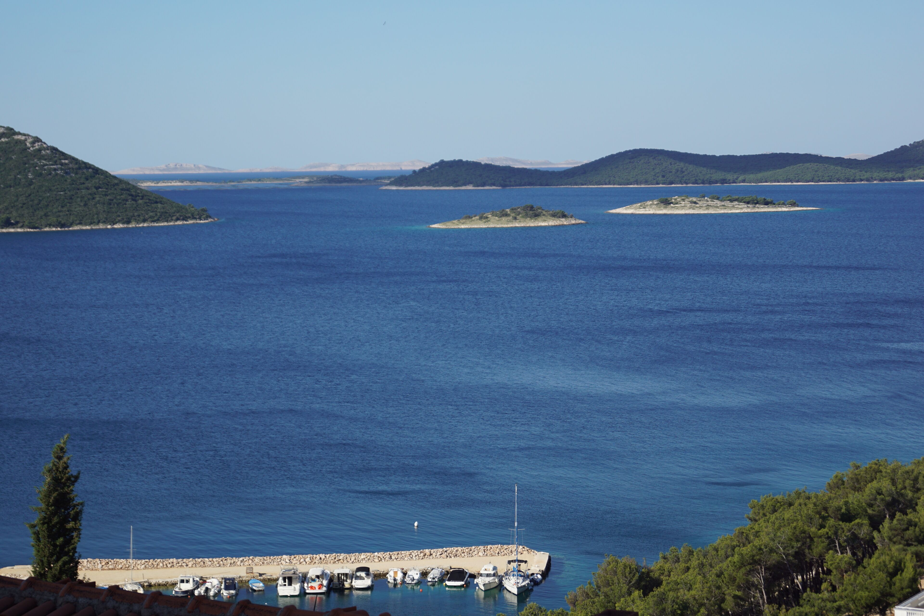 A marina with boats docked, surrounded by clear blue water and distant islands.