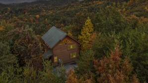 A cabin surrounded by dense forest with a mountain range in the background. - Bella Yani - Hot Tub, Pool Table, & Air Hockey! (Sevierville)