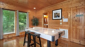 A wooden-floored room with a foosball table, a bar stool, and a sign indicating a laundry area. - Bella Yani - Hot Tub, Pool Table, & Air Hockey! (Sevierville)