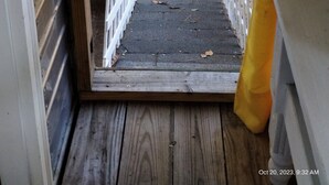 Una escalera de madera que conduce al exterior, con una cerca de piquetes blancos en la parte superior.