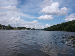 Ein ruhiger See unter wolkenloser Himmel mit vereinzelten Wolken.