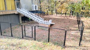 Un espace extérieur clôturé, doté d’une rampe en bois menant à une plateforme surélevée.