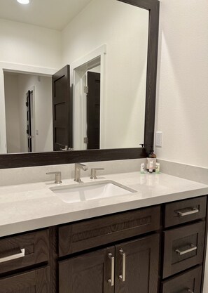 A bathroom with a white sink, dark wood cabinets, and a large mirror. -  Modern Rustic with 2 Car Garage (Mammoth Lakes)
