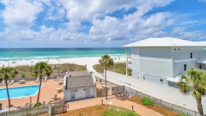 Une propriété située en bord de mer, dotée d’une piscine, de chaises de plage et offrant une vue sur l’océan.