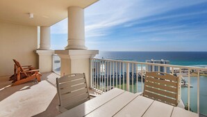 Ein Balkon mit Tisch und Stühlen, mit Blick auf einen Strand und das Meer.
