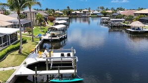 A marina with boats docked, a dock with a boat, and a building with a glass facade. - SW CAPE CORAL: 5 BR 4 BA CANAL HOME with BOAT DOCK  w/heated / lit pool, jacuzzi (Cape Coral)