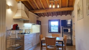 Une cuisine avec des poutres en bois, un fourneau, un four à micro-ondes et un coin repas comprenant des chaises et une table.